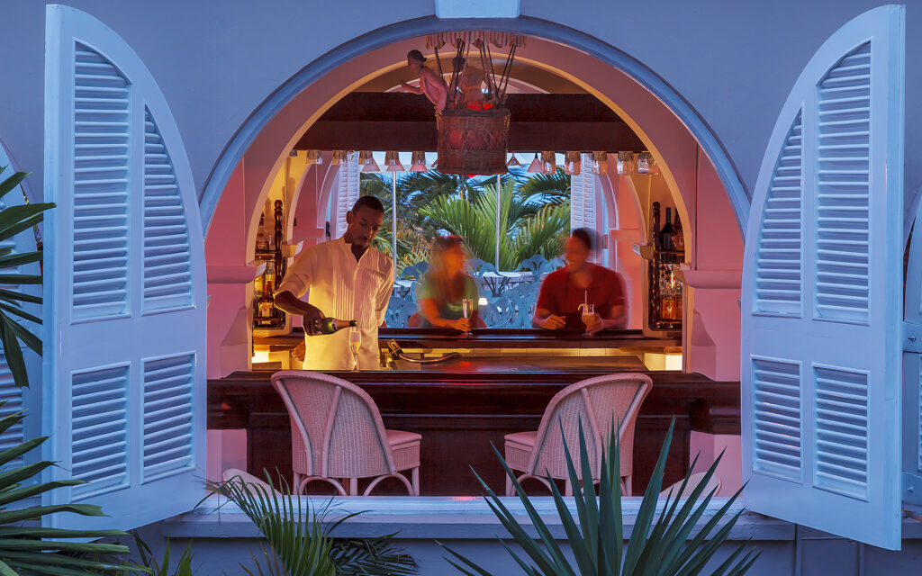 view of a bar area at night from a window with two white shutters open