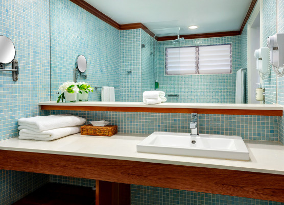 bathroom vanity area with blue tile walls, wooden shelving, and a large mirror