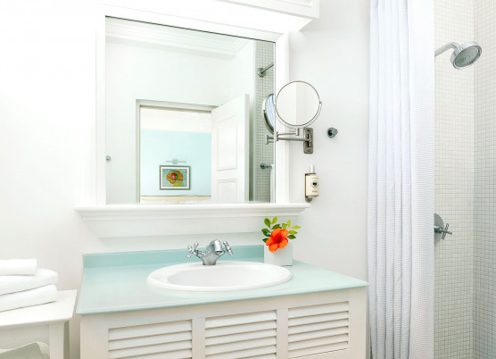 bathroom area with white cabinets, light blue countertops, shower, and white towels
