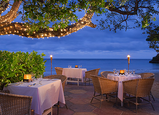 white table cloth covered tables on an outdoor patio overlooking the ocean