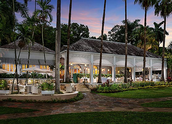 long white gazebo set up with dining tables underneath at sunset