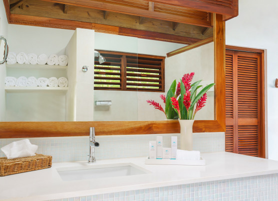 bathroom with wooden accents, white counters, sink, and decorative flowers