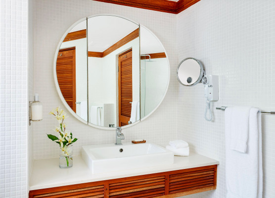 a bathroom vanity with large round mirror and wood accents