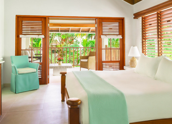 a bedroom with an open veranda and large bed with turquoise decor