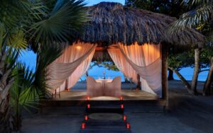 private dining table under a tiki hut on the beach at night