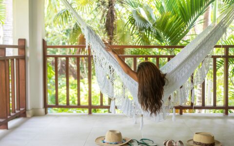 behind view of a woman laying on a hammock on a private balcony